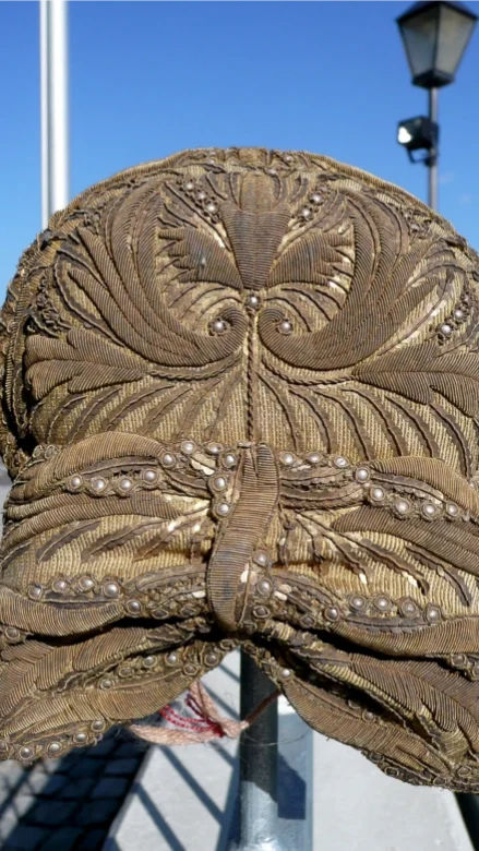Detailaufnahme der Rückseite einer historischen Radhaube mit feiner Silberdraht- und Metallstickerei.