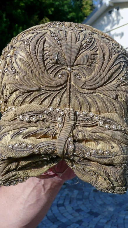 Detailansicht der Vorderseite einer Radhaube mit Goldlahn, Perlen und floralen Stickmustern.