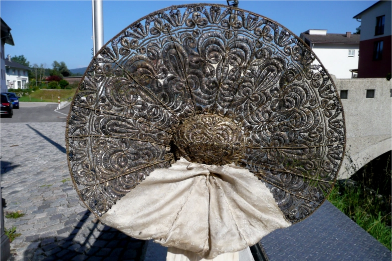 Rückansicht einer historischen Radhaube mit filigranem Metallgeflecht und Seidenschleife aus der Sammlung der Hofmühle.